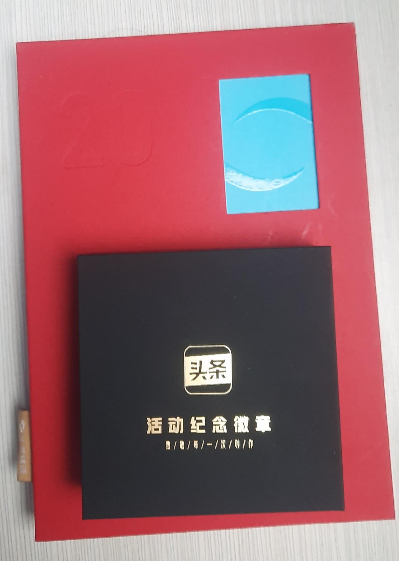 收到今日头条发来的奖励啦，2026年定制台历、笔记本，还有一枚精致纪念徽章。
