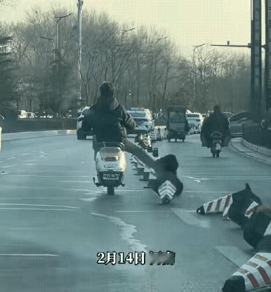 怎么可以这么讨厌
男子骑着电动车，在大马路上，边骑边伸出一条腿，踢倒了用作标记的