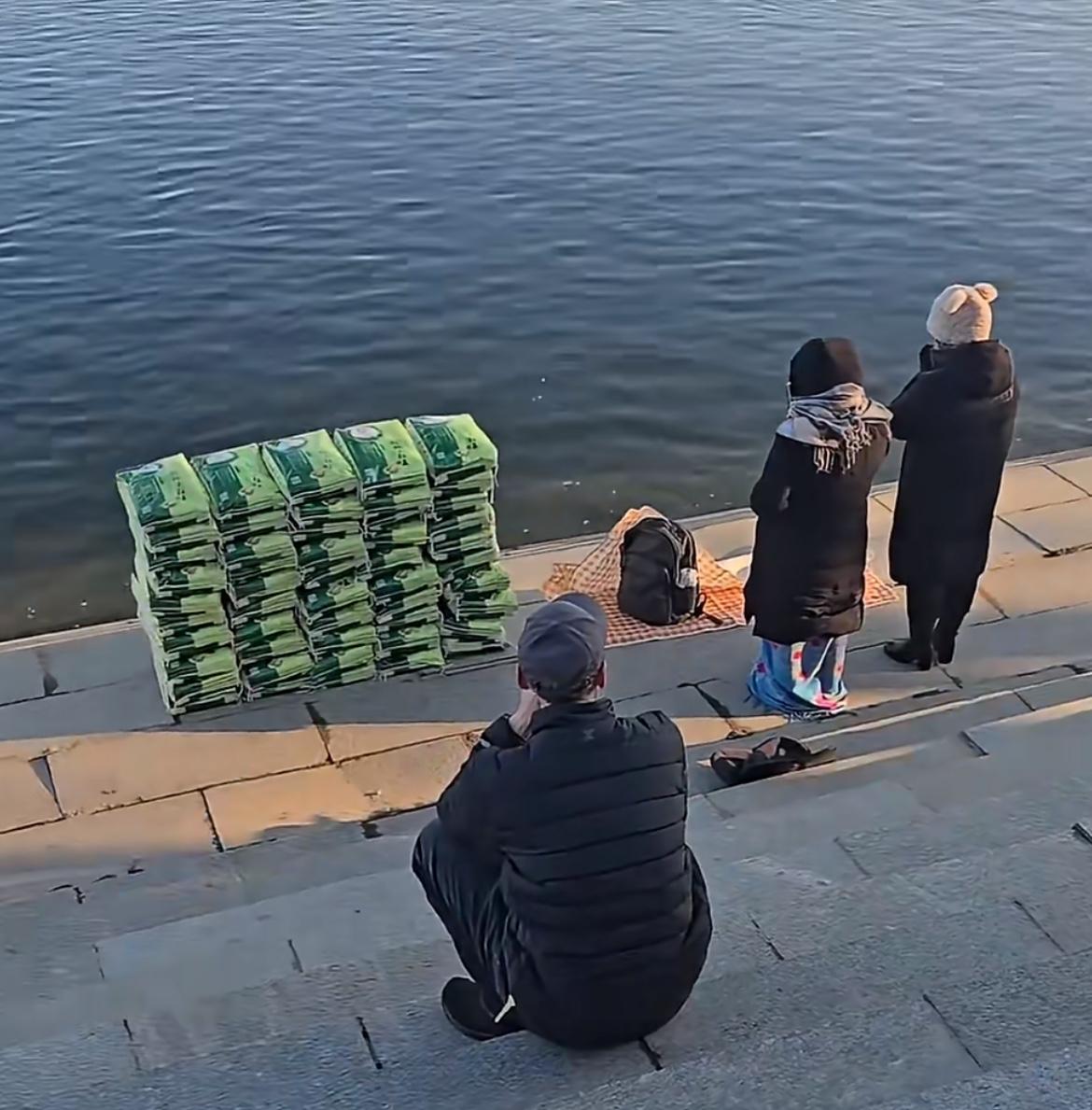 辽宁丹东网友拍到，一妇女河边放生大米祈福，这是做了啥亏心事，竟然要如此糟蹋粮食。