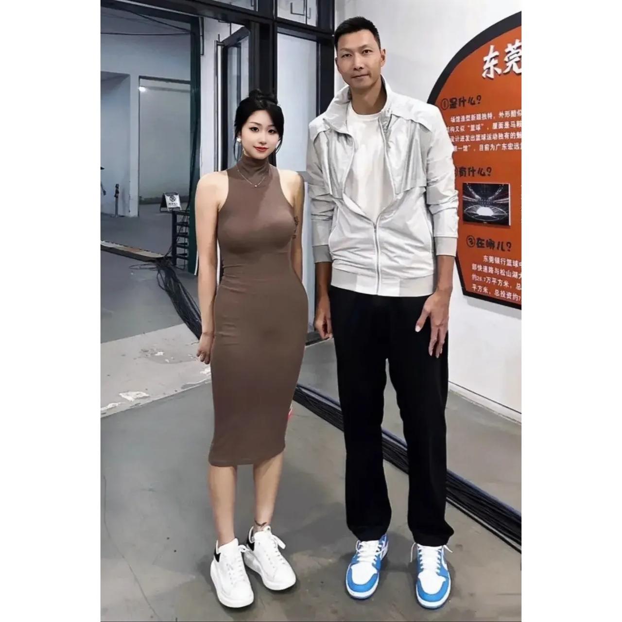 一代篮球巨星易建联与年轻貌美的女球迷早期在东莞的合影，女球迷五官秀丽，身着棕色高