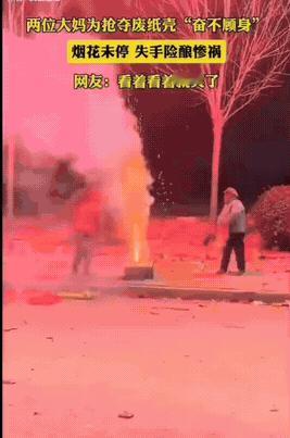 烟花正在燃放，可是两位大妈却争抢着烟花外面的纸壳箱子，两位大妈在你争我夺的过程中