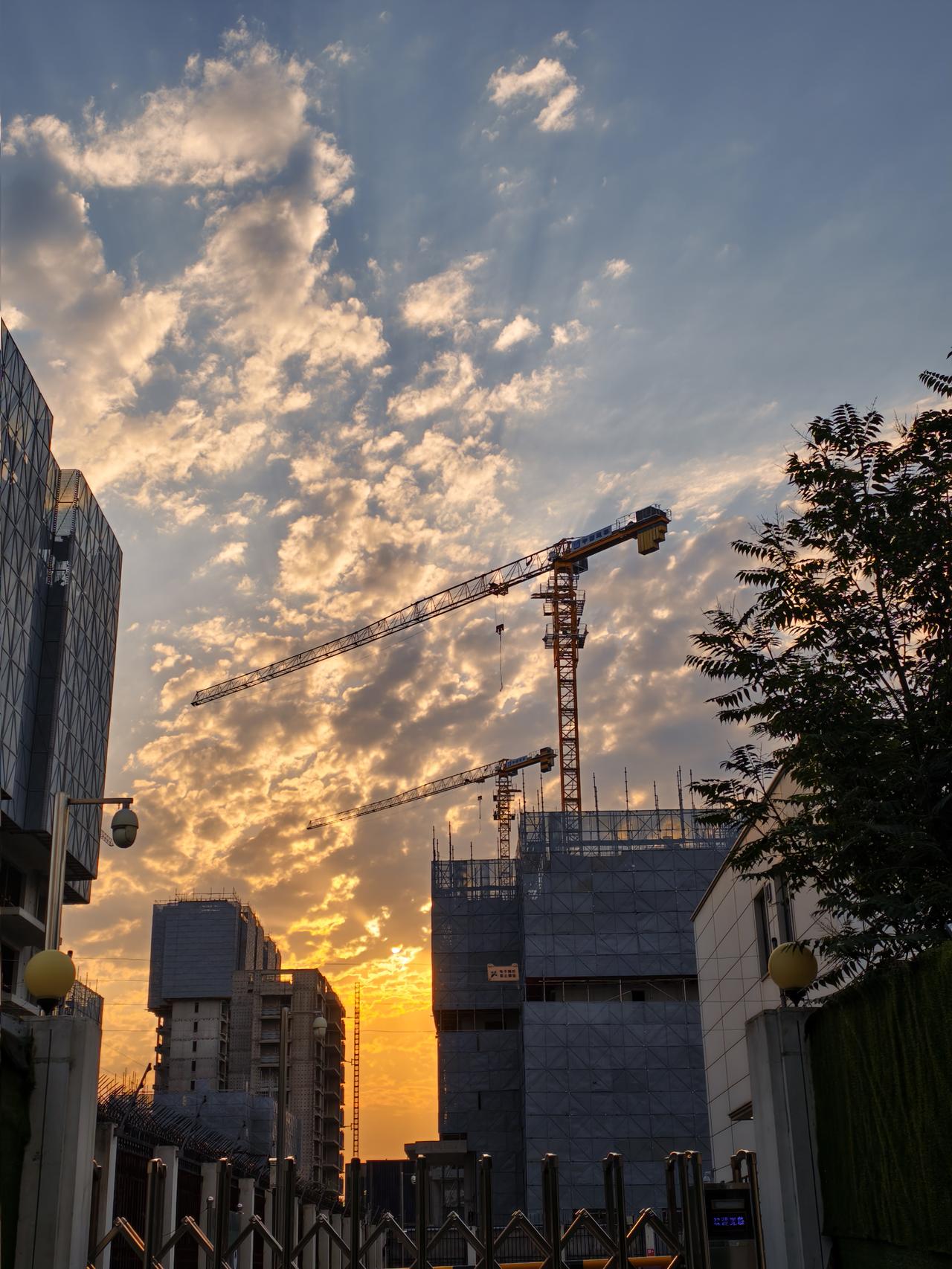 清晨，城市更新改造项目施工工地上的楼宇和塔吊，高耸于朝霞和彩云间，形成美妙绝伦的