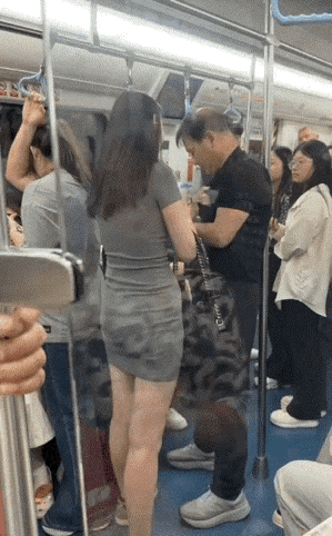 地铁车厢高挑女子正在查看男性老者的手机视频，当看到有她的偷拍照片上去给老者一个耳