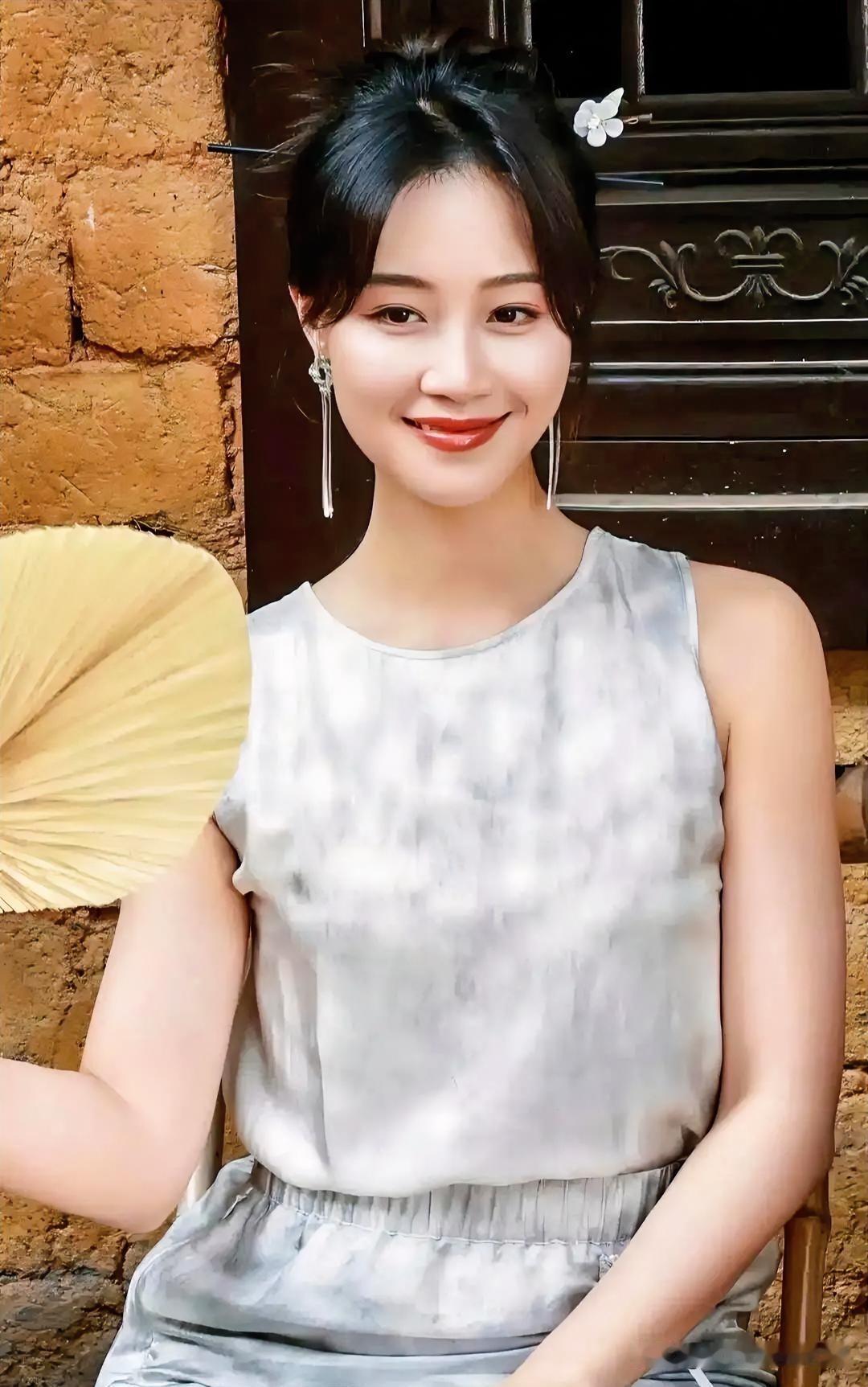 素雅衣袂映衬温婉笑意，古朴门庭间执扇浅坐，将东方雅韵与闲适时光悄然定格。