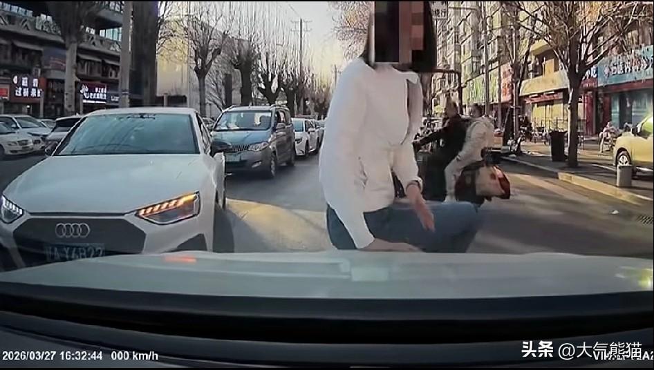 这位女子为了自己的车辆能转弯，竟然人肉阻挡车流，一屁股坐到对面车辆的引擎盖上，这