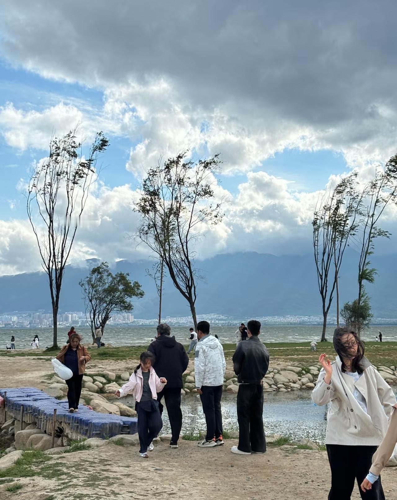 郭涛带着儿子在洱海边做公益，两人手里拿着黑色塑料袋边走边捡垃圾，不一会就把袋子装