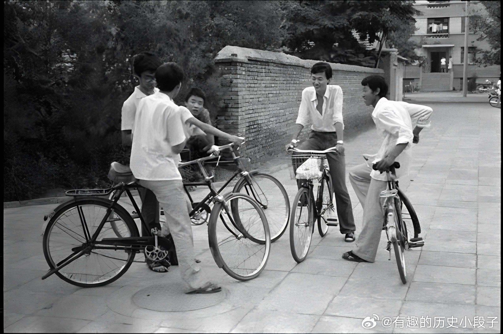 这张黑白老照片定格了上世纪80年代的街头瞬间：几位穿着白衬衫的年轻人骑着“二八式