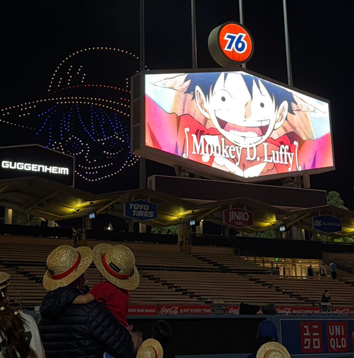 MLB美国职棒大联盟道奇队海贼王之夜现场：戴着草帽的父子看着大屏幕的路飞。海贼王