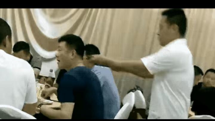 酒席上，一个男人正低头夹菜。身后突然窜出个人，二话不说，一根钢丝锁直接套他脖子上