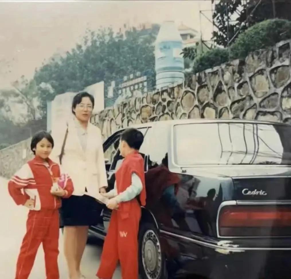 90年代，一位妈妈带着她的两个孩子，在她的车子旁边留影。
