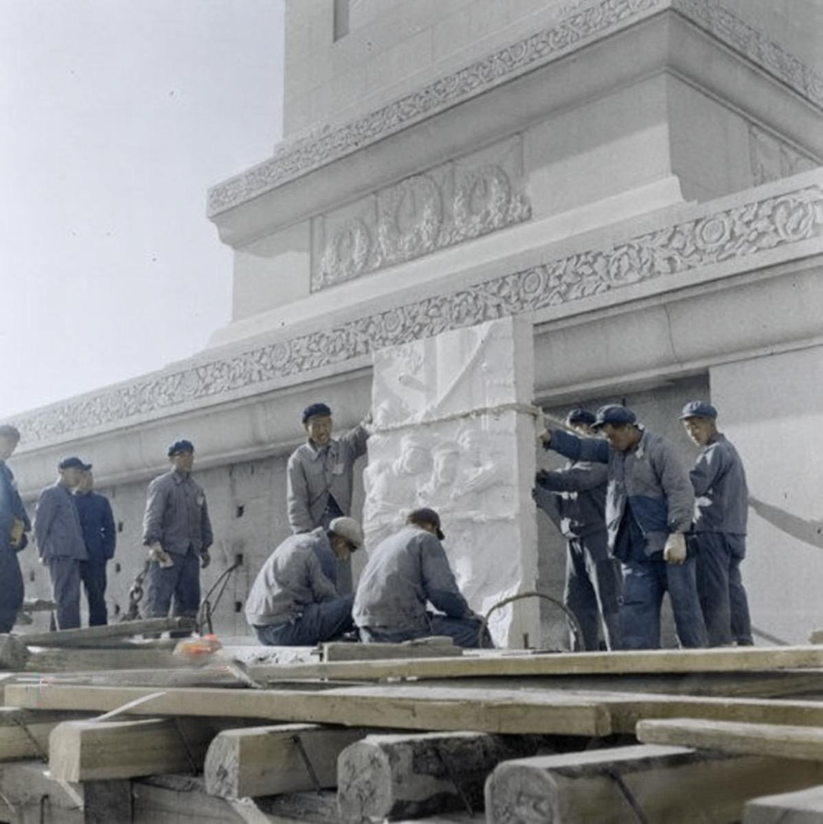 1957年“五一”前夕，工人们正合力吊装一块大型汉白玉浮雕板，这是纪念碑须弥座上