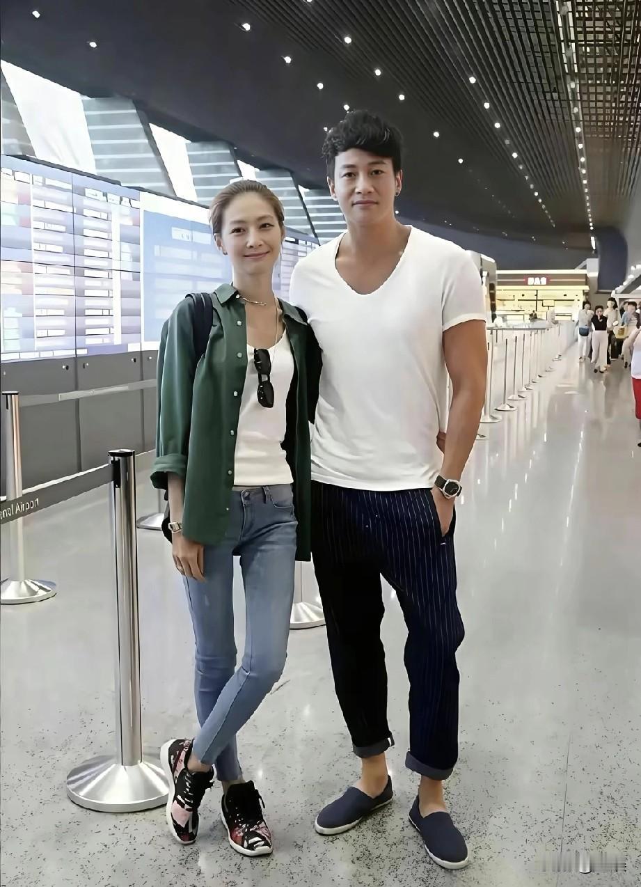 在机场何润东与妻子林佩希同框，他简约白T配条纹裤尽显型男魅力，她墨绿衬衫搭牛仔裤