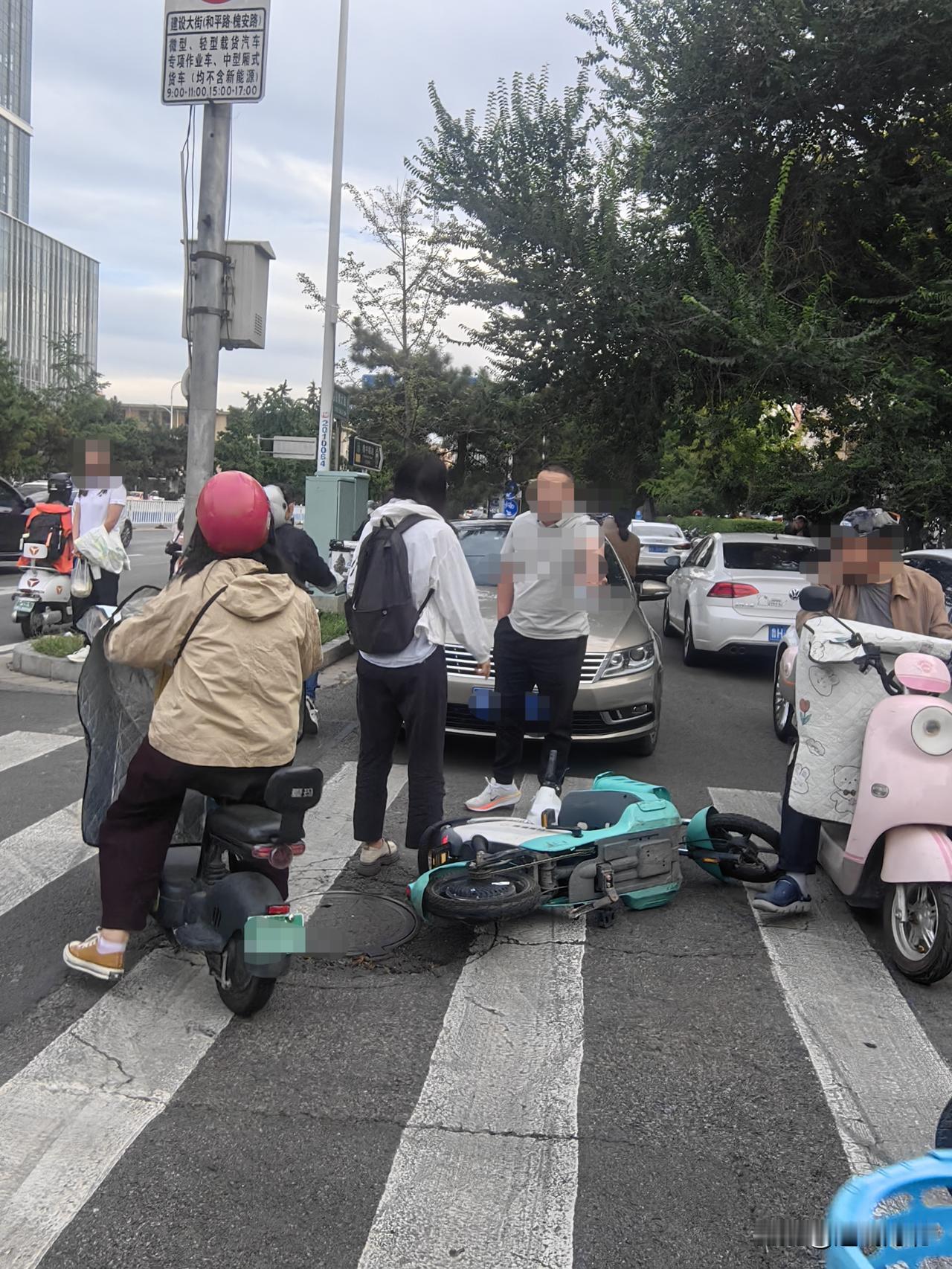 事故现场，电动车侧翻倒在斑马线上，涉事机动车停在路口，路口过往车流人流量较大。