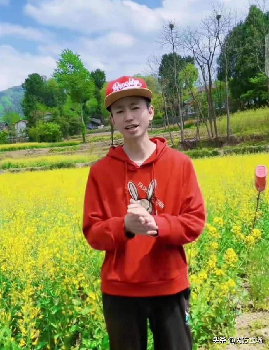国际巨星庞麦郎戴着顶红帽子，站在金灿灿的油菜花地里，对着手机镜头认认真真唱《我的