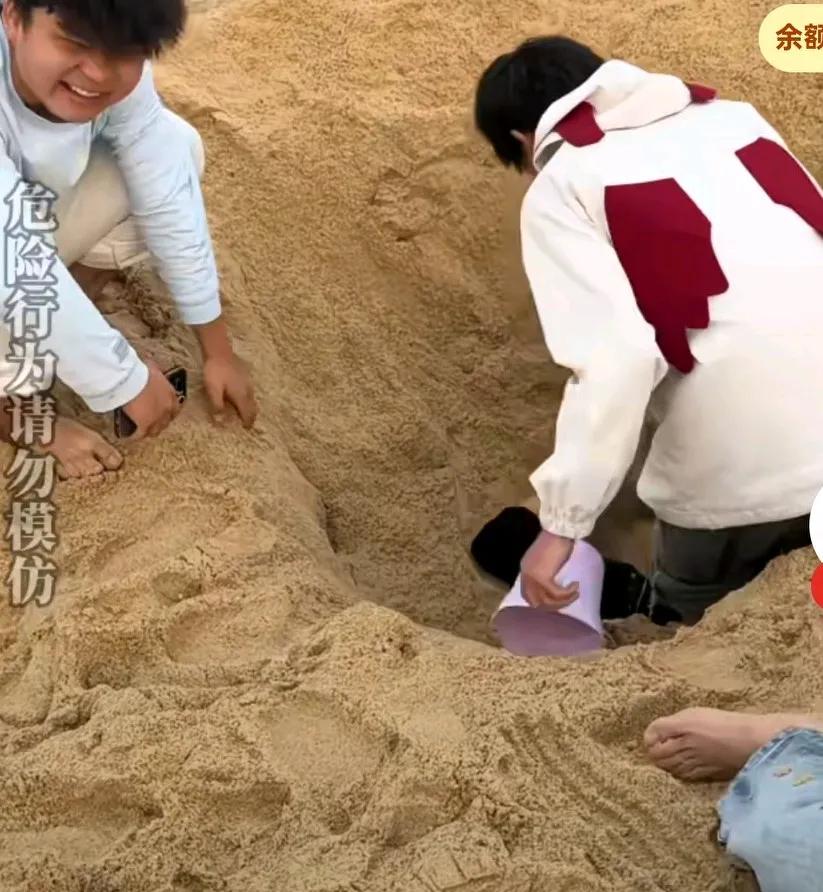 众人在沙堆旁将伙伴埋进沙土里，不承想沙子太过紧实男子出不来了，
这时大家才有点慌