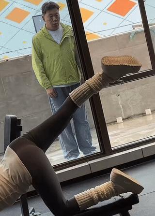 一名中年男子站在玻璃门外正在聚精会神的观看里面的女孩练习瑜伽？
结果他被突然赶来