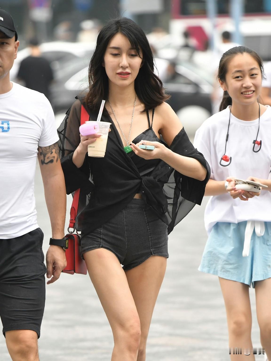 今天走在街头，我穿着一件黑色透视衬衫，搭配深色牛仔短裤，脚踩黑色凉拖，手拿一杯冰