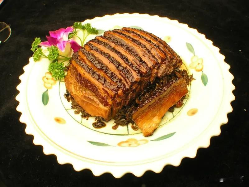 精选三层肥瘦相间的土猪肉，先焯水去腥，再用老冰糖炒出糖色，把肉皮煎得油亮红亮。