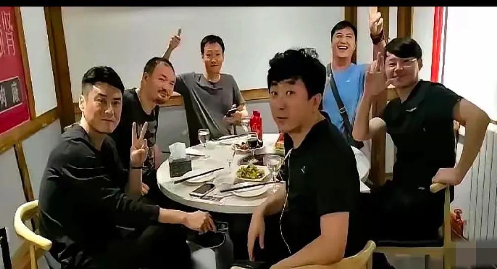 辛柏青与老友围坐小馆，面带微笑，气色不错，眼里有光，些微削瘦，一手拿着手机，一手