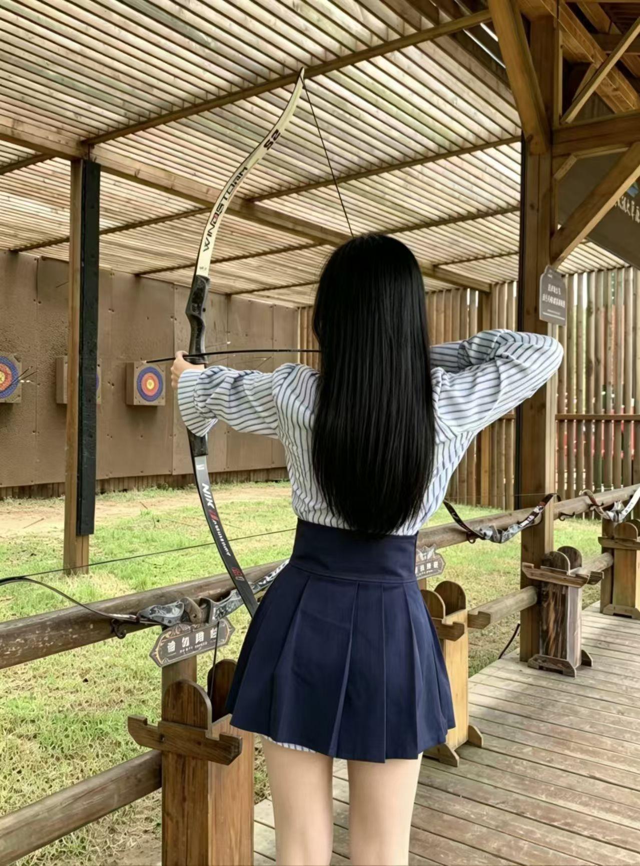 少女在木制射箭场拉弓，感受传统与现代的碰撞。