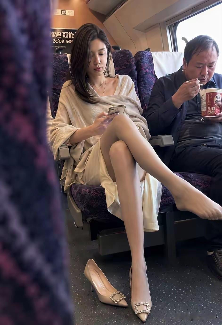一位面容姣好气质也很好的美女旁若无人翘着二郎腿，边上的男乘客端着方便面吃着正香。