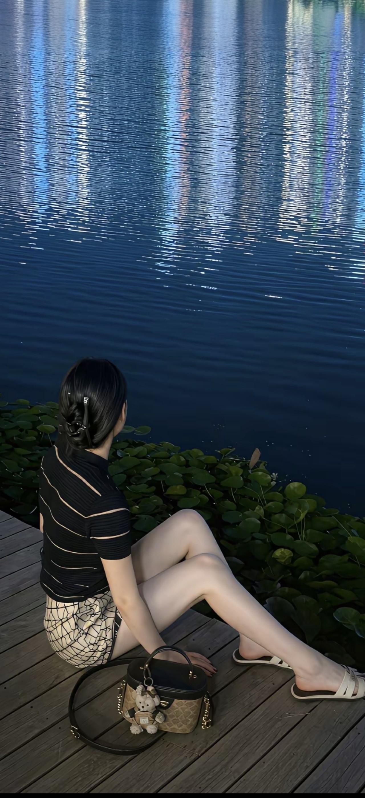 一个女孩坐在湖边，看着水面发呆。