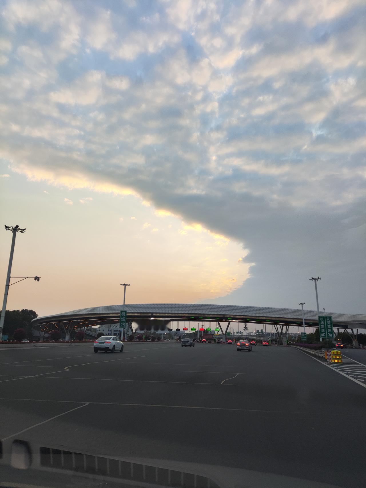 车行驶在广州机场高速，头顶的云像被落日裁开一道缺口，暖金的光从云缝里漫出来，把半