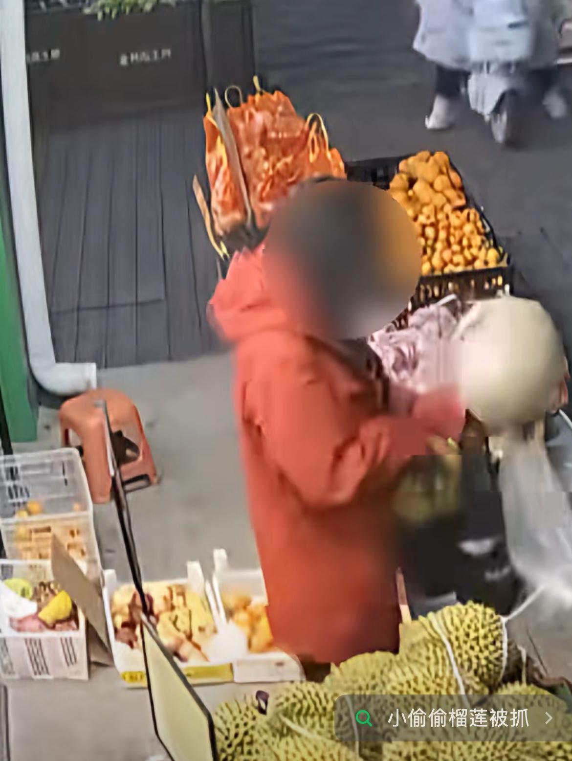 一女子在水果摊将两个榴莲偷偷放到包里，老板发现后，将榴莲从她包里拿回来，刚要报警