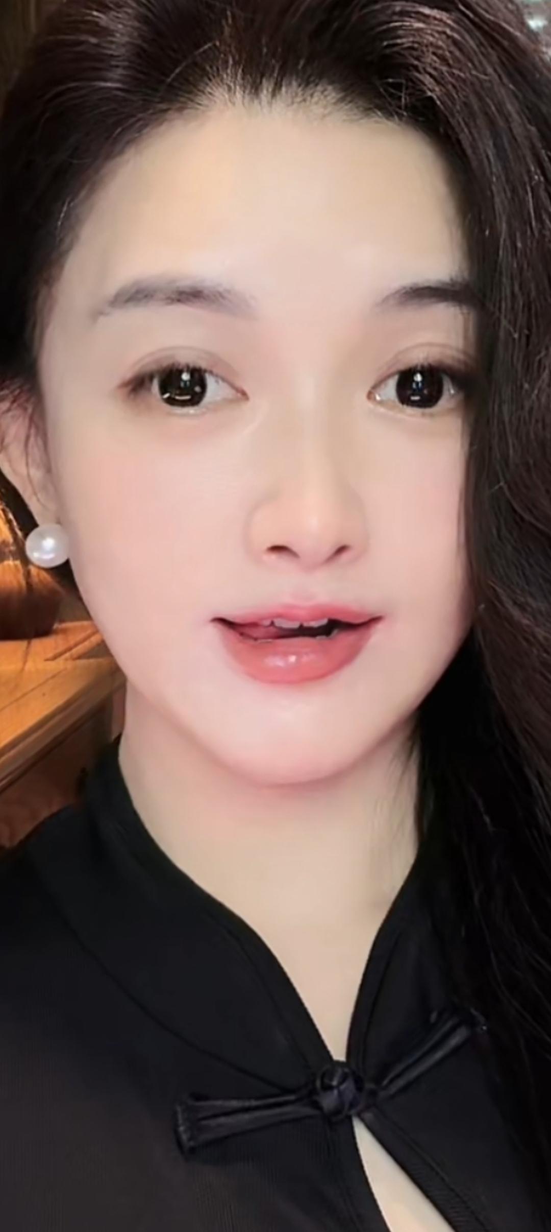 这个美女穿着黑色衣服，戴着珍珠耳环。