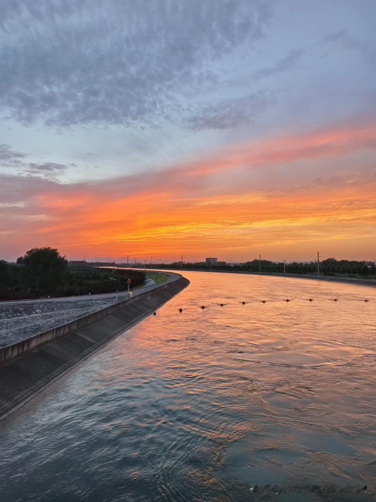 运河边的落日太绝了！
太阳慢慢往下溜，
把天和水都染成了橘红色，
波光粼粼的，