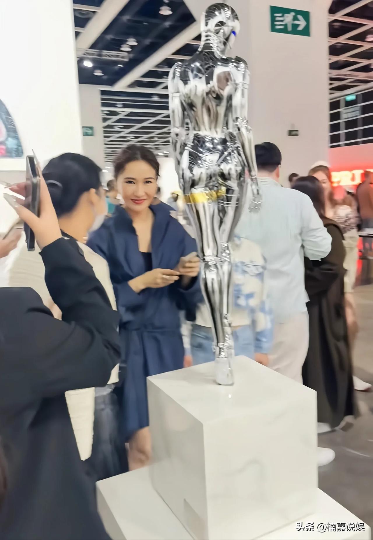 黎姿现身看艺术展，穿着一身深蓝色套裙，脚踩厚底靴子，扎着丸子头，本人看着好年轻，