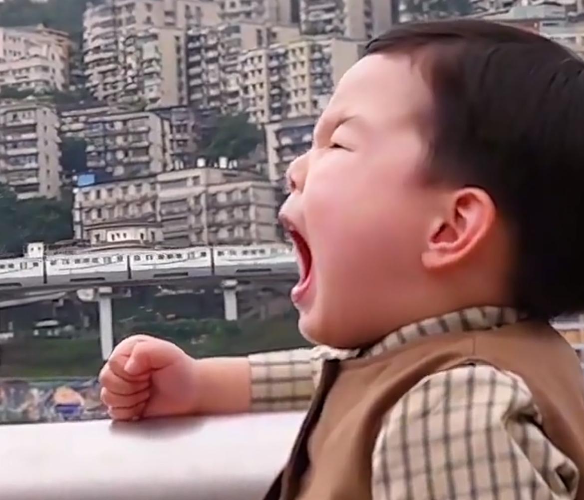 在著名的“单轨穿楼”李子坝站，一名萌娃在摄影师的指挥下，上演了一场可可爱爱的“吃