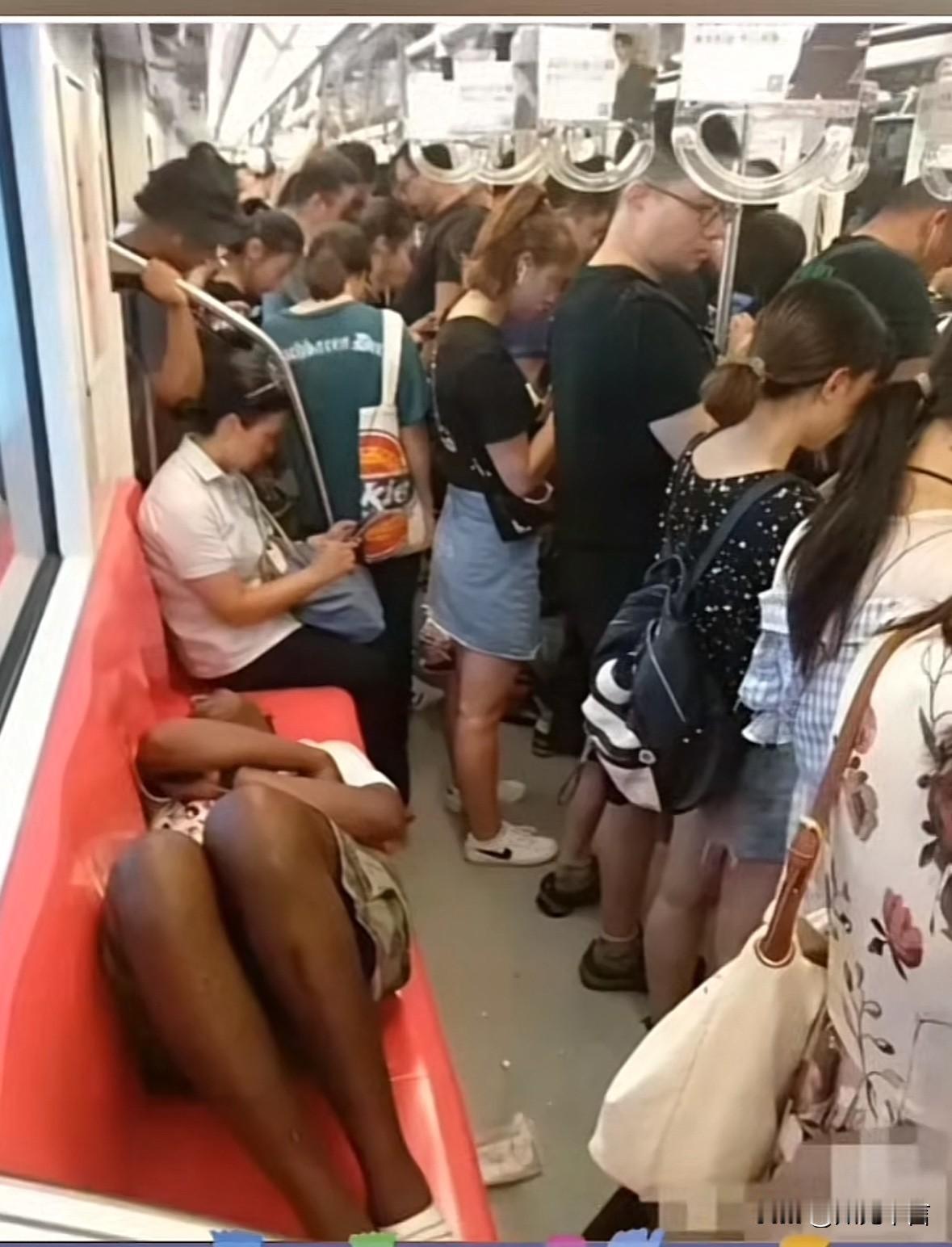 这位“外国友人”不知道昨晚干什么去了这么累，在地铁座椅上躺着就睡着了，而旁边的人