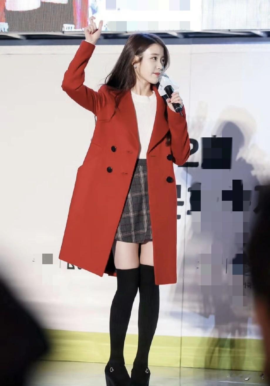 李知恩（IU）在活动现场光彩照人，红色大衣衬得她明艳大气，内搭的白色上衣与格纹短