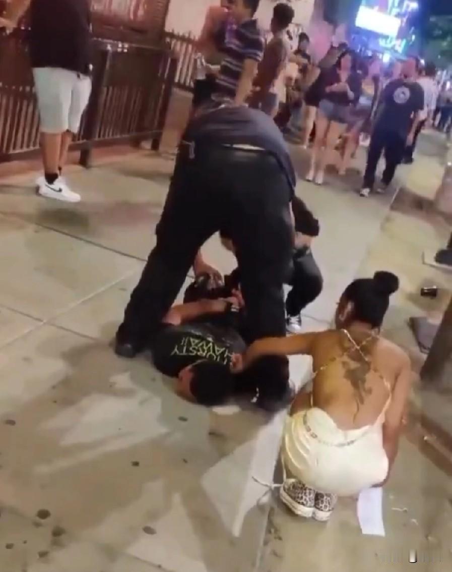 纽约街头这一幕太魔幻了！一名男子被警察按倒在地，旁边一男一女路人见财起意，瞅准警