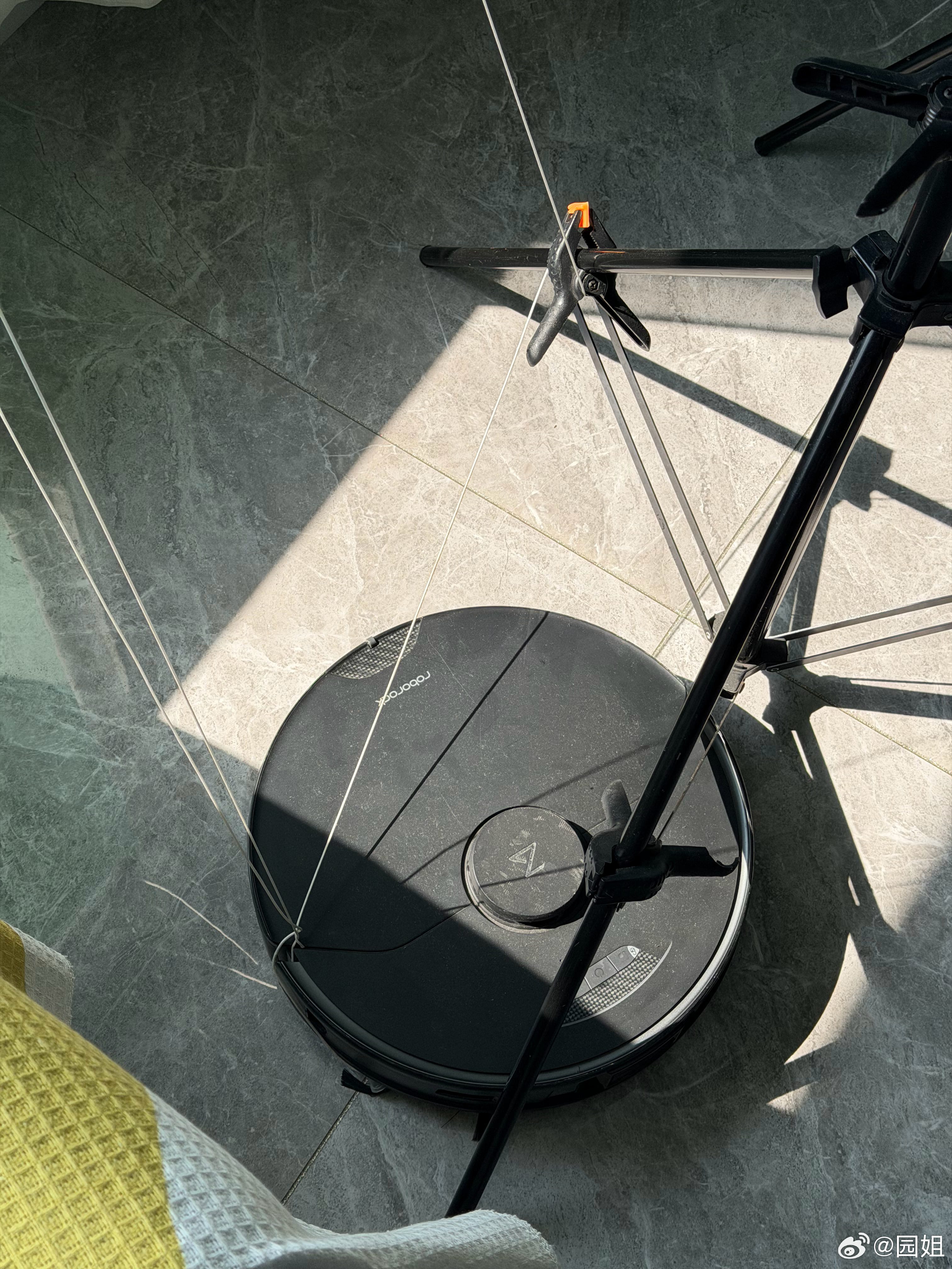 一台被绑架的扫地机器人，不知道怎么把百叶窗拉绳绞进去了，彻底放弃抵抗认输，这可能