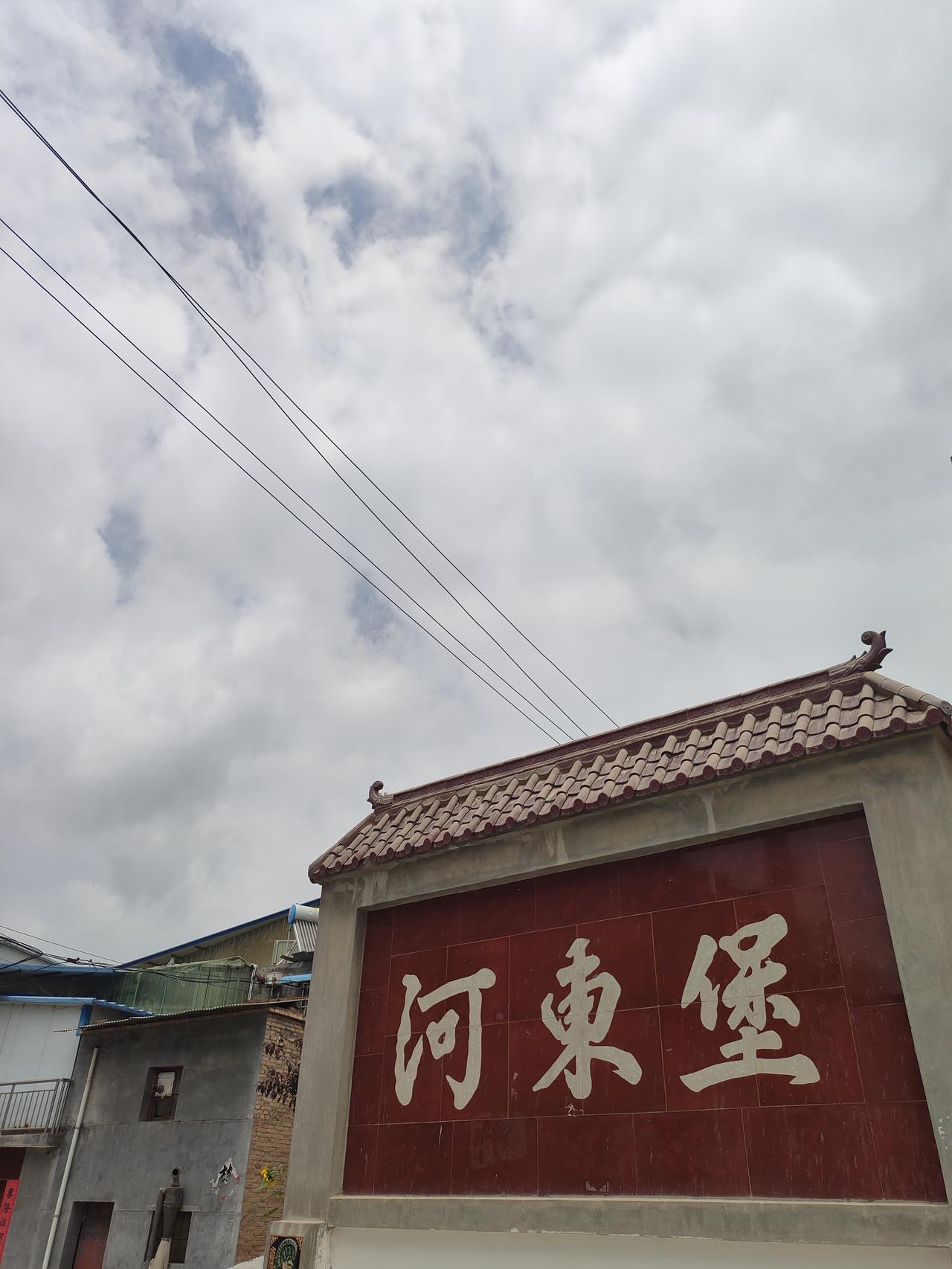今日随手拍踏进河东堡，抬头是层层云絮，院内向日葵兀自舒展枝叶。老屋、老树、交错电