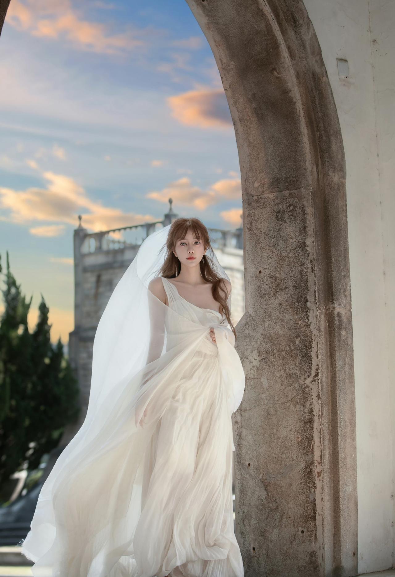 一袭飘逸的白色长裙，搭配着轻盈的头纱，这一造型被形容为“古希腊掌管浪漫的神女”，