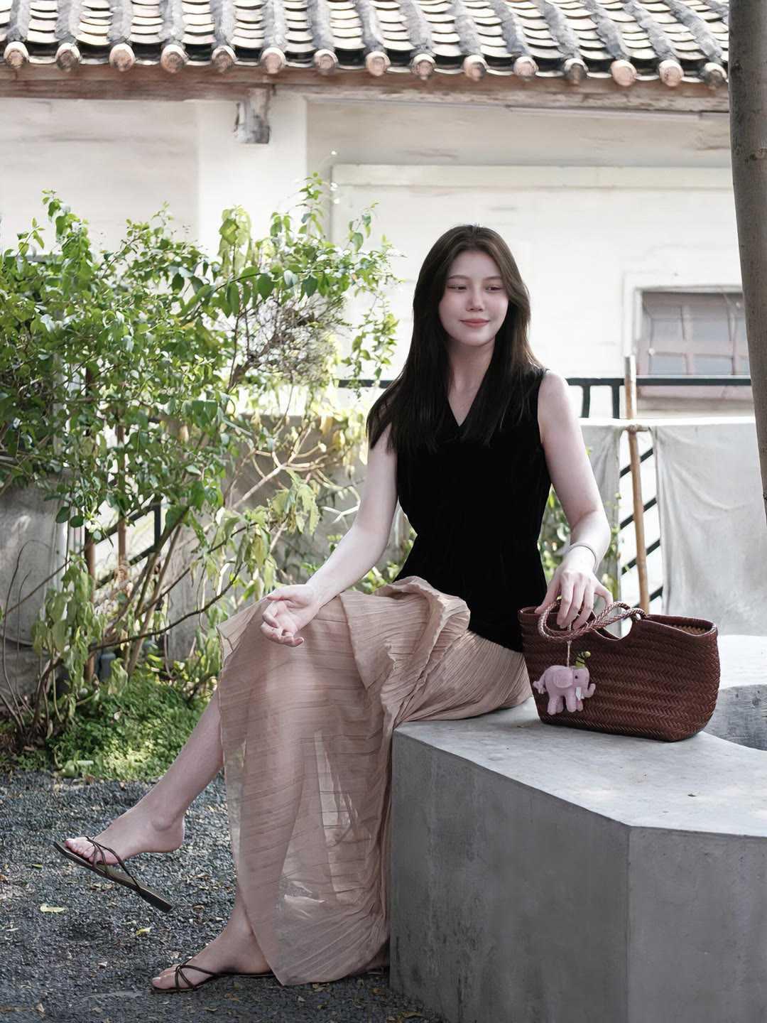 黑丝绒无袖上衣搭配奶茶色压褶半身长裙，冷暖色调碰撞，自带温婉松弛的氛围感。轻盈褶