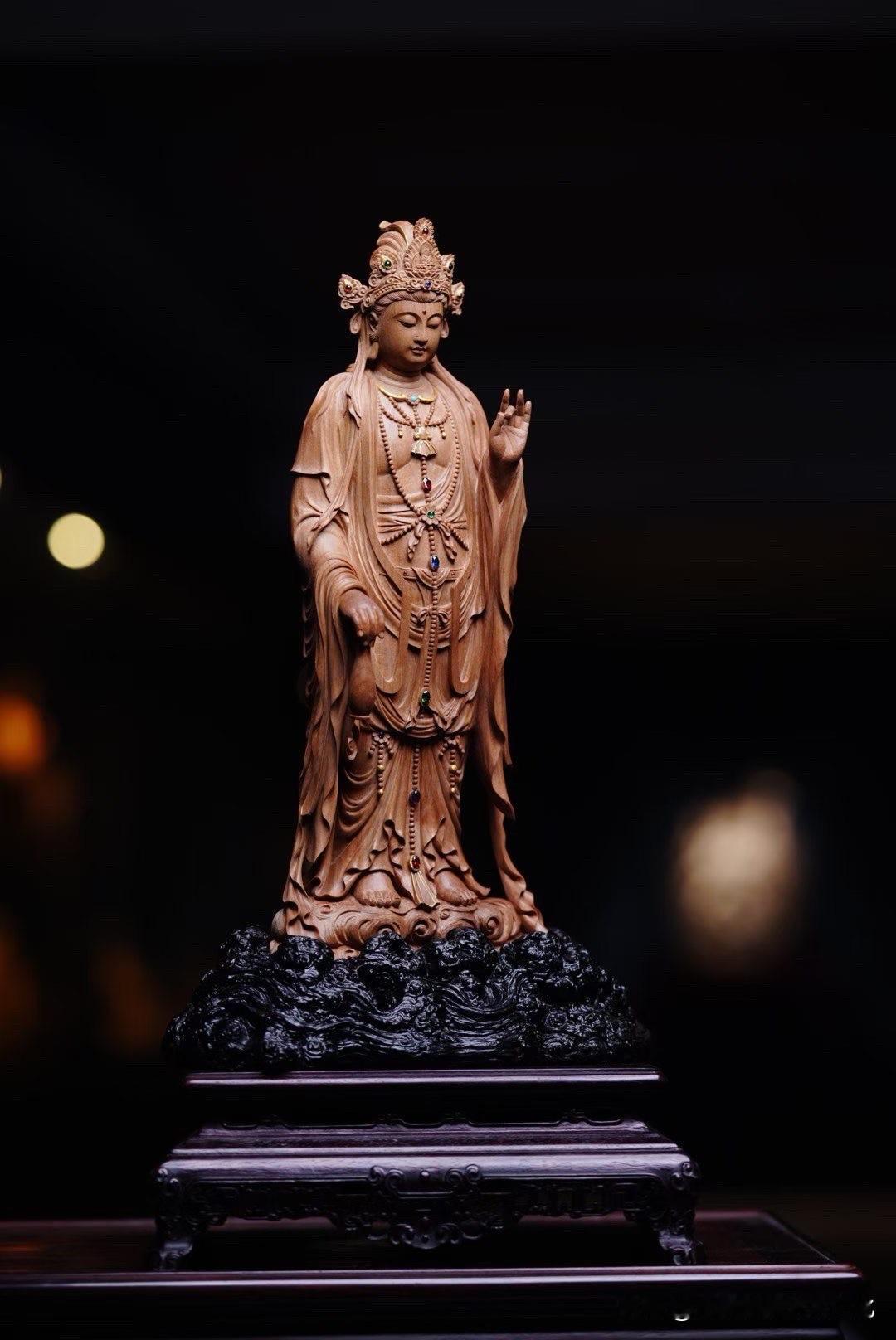檀香温润，观音低眉而立，静静一望，便有一种清雅气息。

左手轻捻净瓶，右手结法印