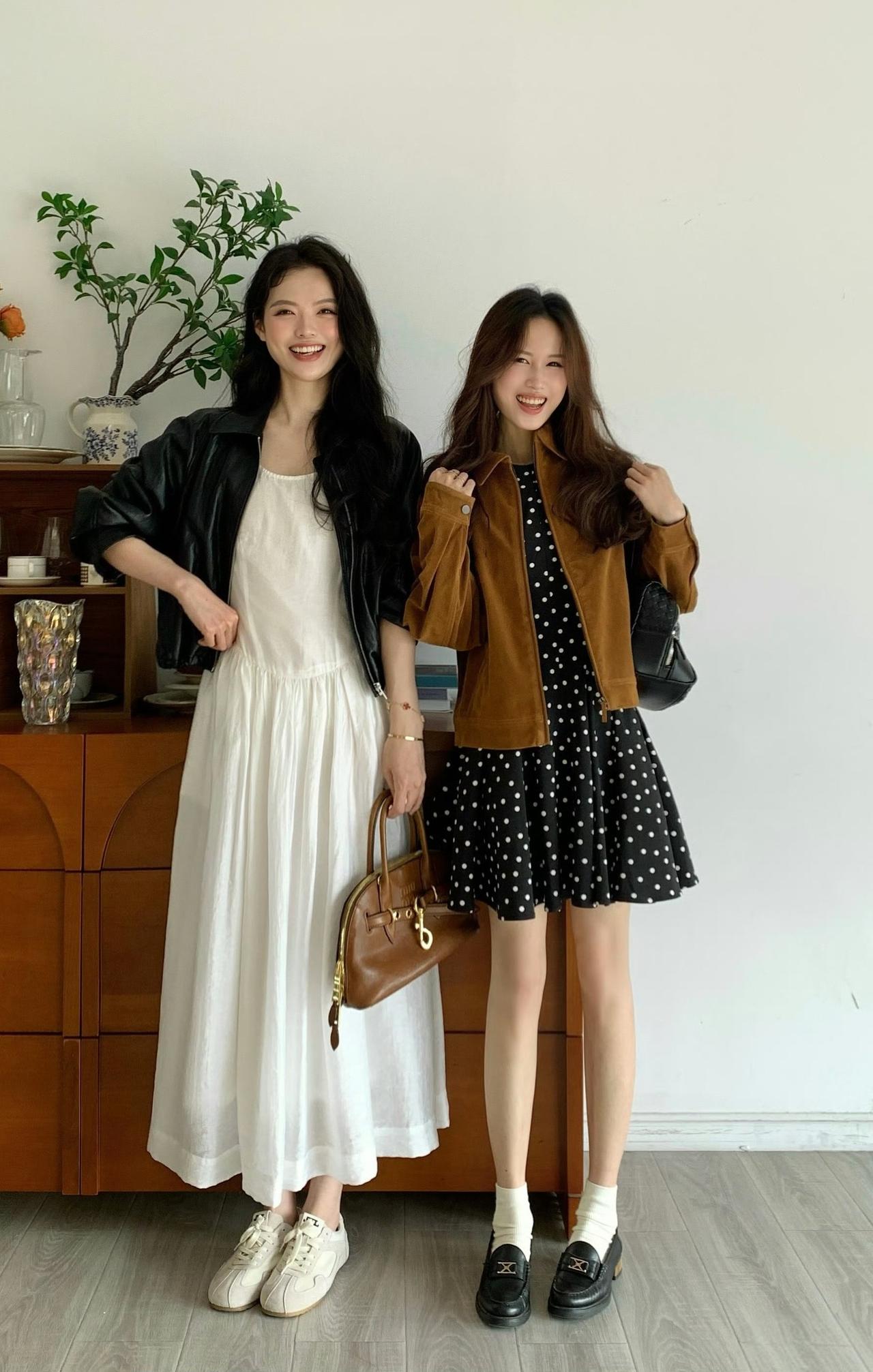闺蜜穿搭👇👇

左边的女生穿着白色长裙搭配黑色皮夹克和白色休闲鞋，手持棕色手