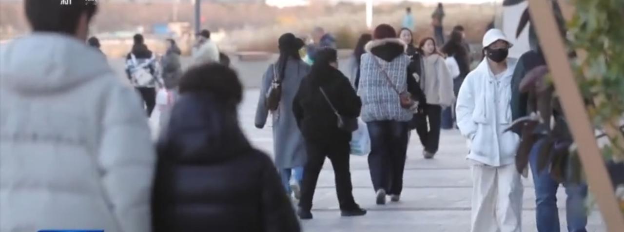 第一张图中，户外步道上人群熙攘，人们身着厚实冬装缓步前行，身影错落间尽显街头的鲜