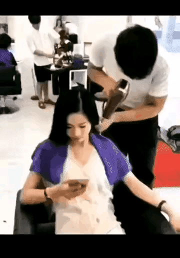 理发店里，理发小哥，给美女吹头发，美女看着手机，谁知，理发小哥，动了邪念，不吹头