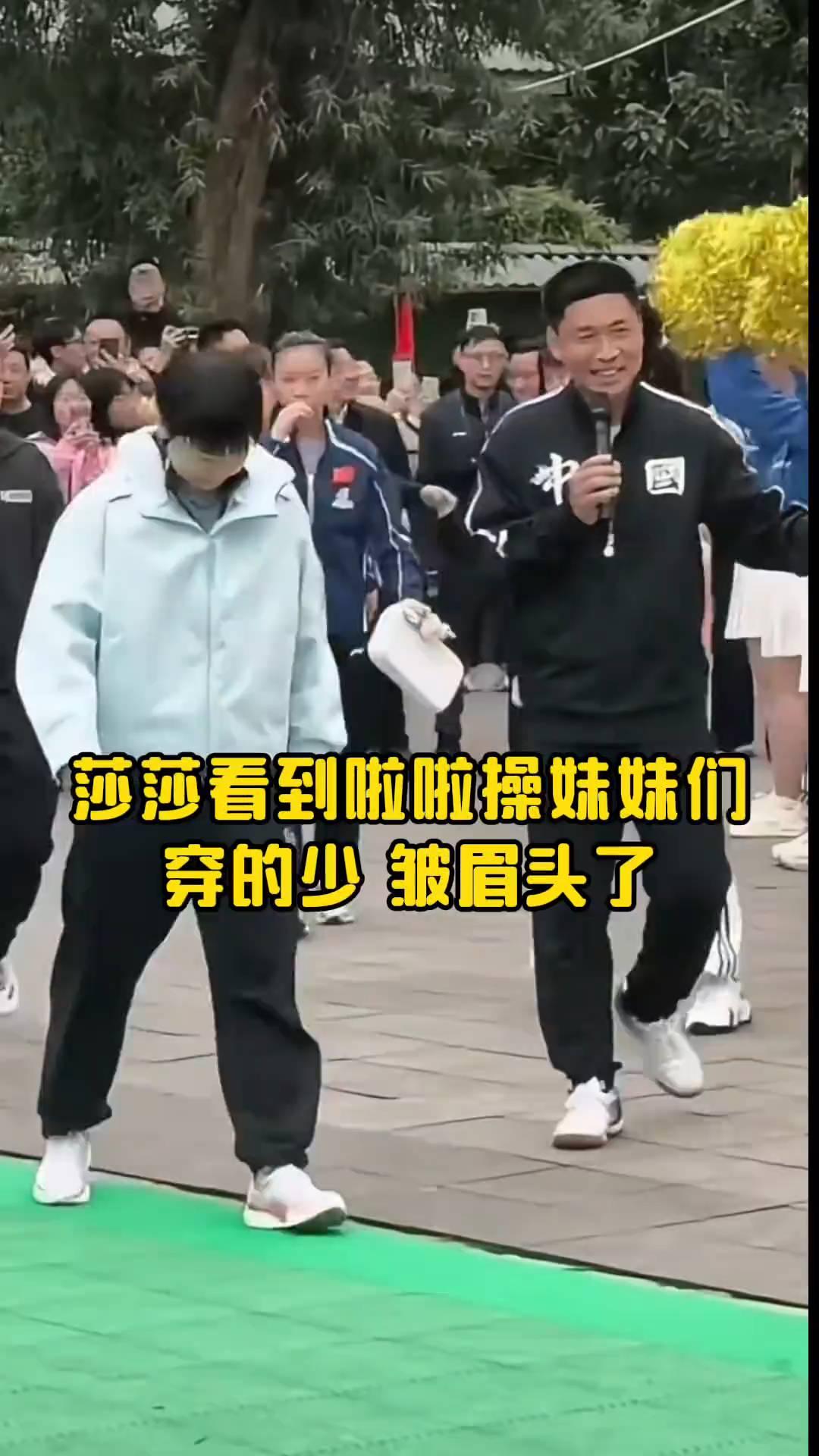 莎莎看到啦啦操妹妹们穿的少皱眉头了。把衣服穿上，冷。莎莎的小腿晃呀晃的，笑意盈盈