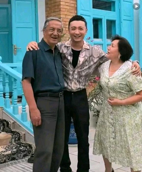 央视主持人尼格买提与父母在老家门口合影，一家三口笑得好开心。