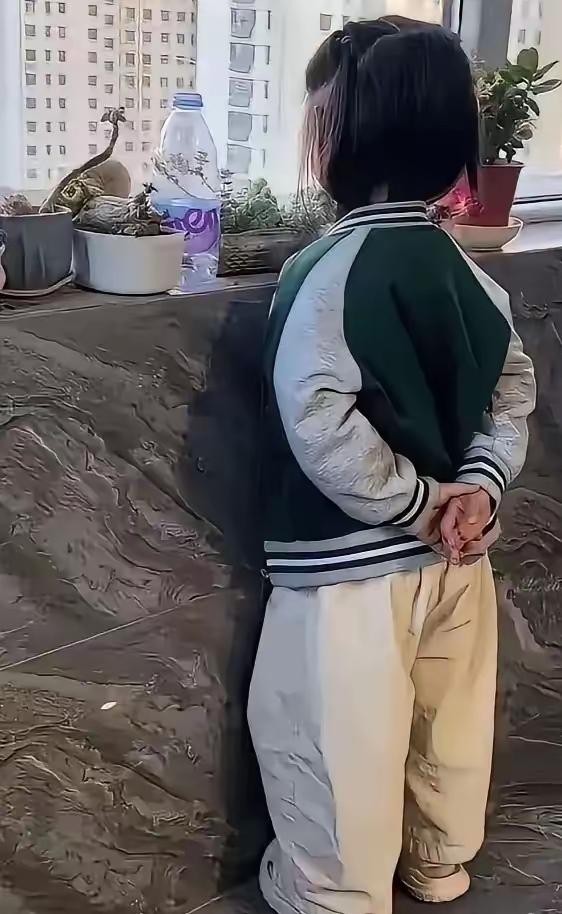 女儿开学第一天就被老师封了一个官，回家后的样子就成这个样子了，表情严肃的站在阳台
