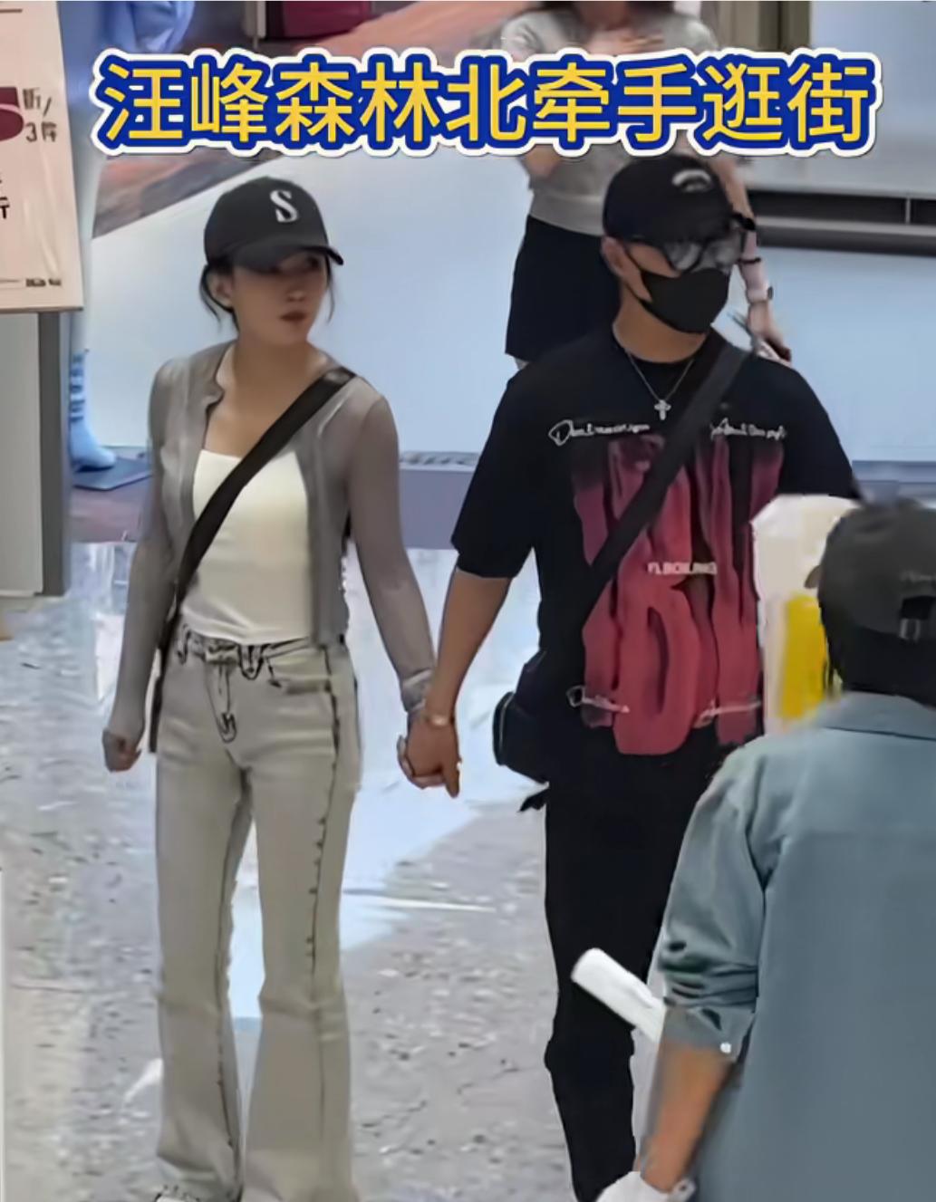 汪峰森林北手牵着手逛街被偶遇，汪峰穿着黑色短袖，戴着鸭舍帽，黑色口罩，包裹严实，