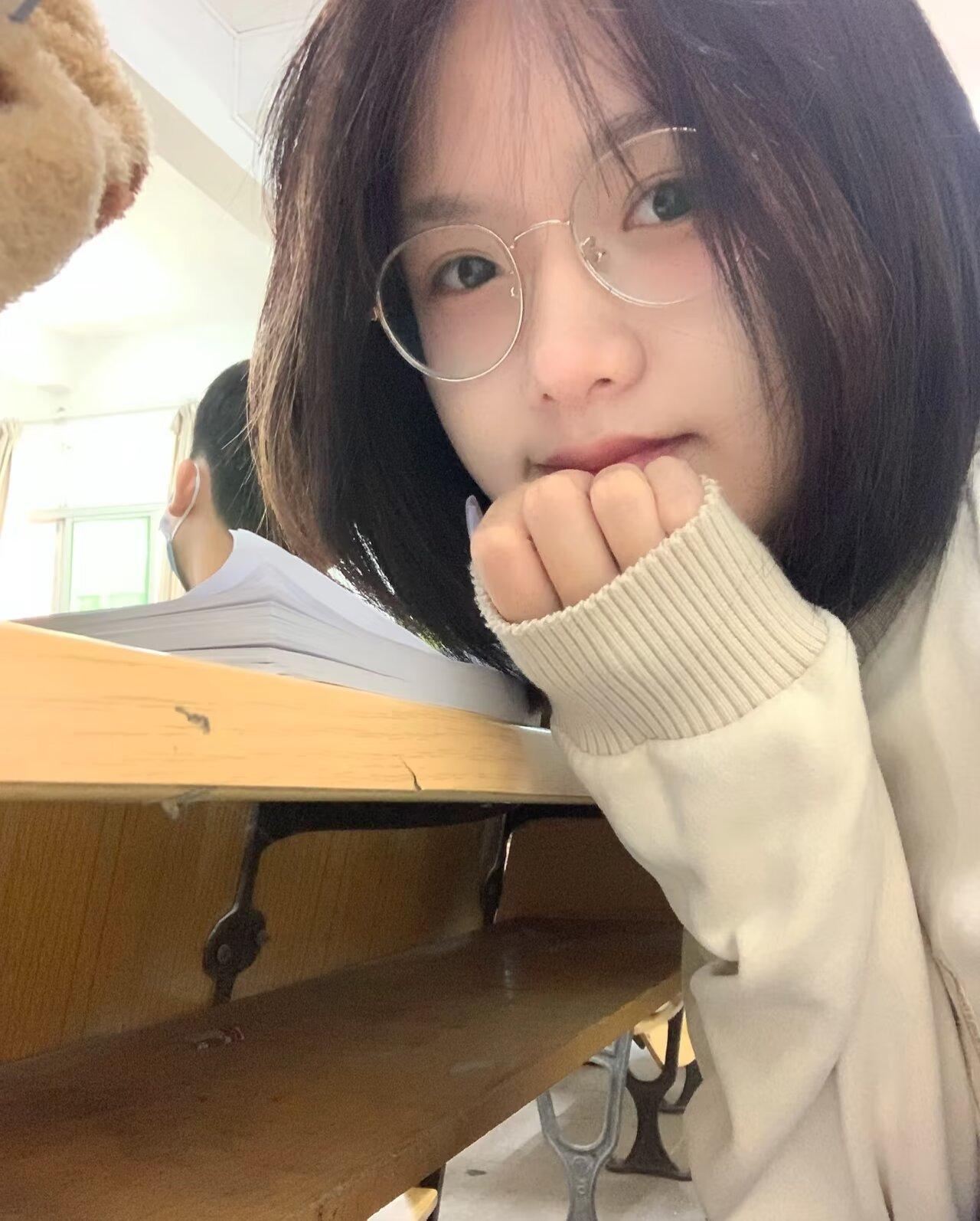 圆框眼镜配齐肩短发，软乎乎的米色毛衣袖口盖住半截手，
托腮时睫毛在镜片后轻轻颤，
