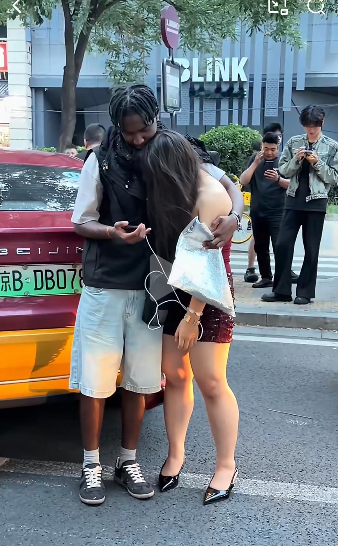 北京工体酒吧一条街门口，一非洲小伙搂着一个中国女孩，路人关切地询问：结婚了吗？小