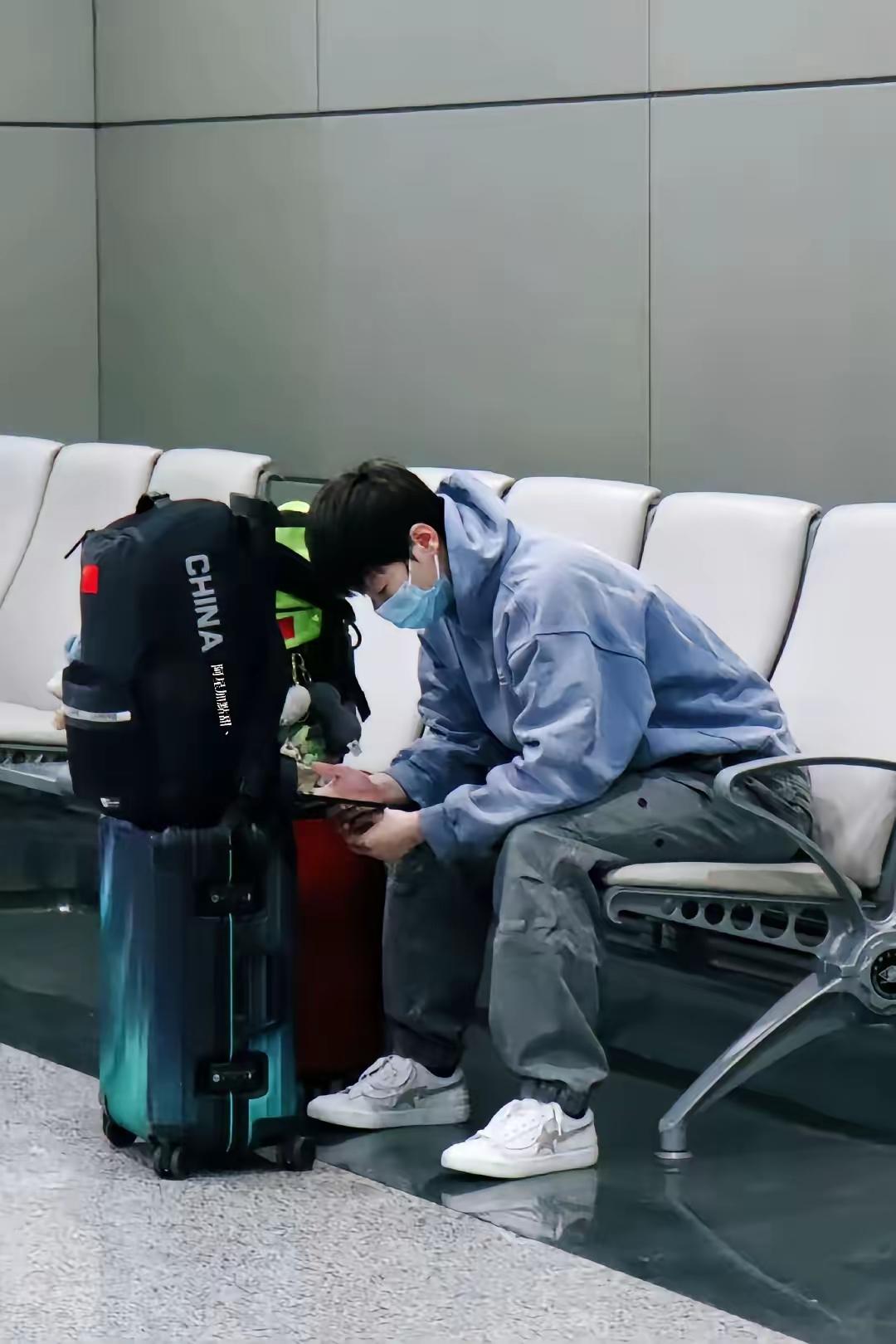 曼昱落地成都机场，脱下黑色羽绒服露出灰色卫衣，顺手把脱下羽绒服塞进黑色行李箱。